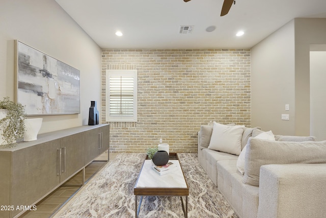 living room with light wood-type flooring, ceiling fan, and brick wall