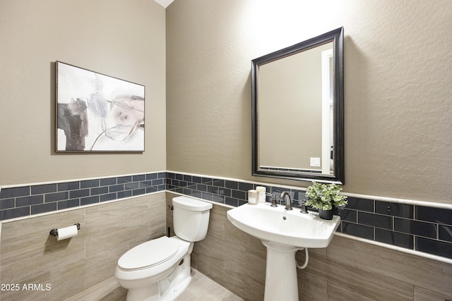 bathroom featuring tile walls and toilet