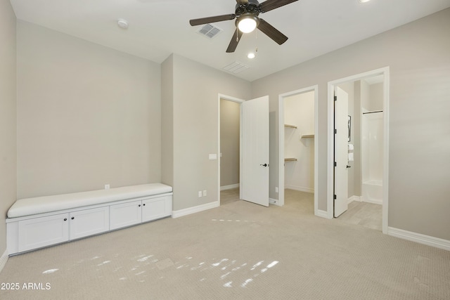 unfurnished bedroom featuring connected bathroom, a spacious closet, light colored carpet, a closet, and ceiling fan