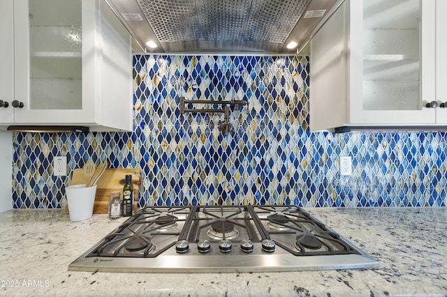 kitchen with light stone counters, decorative backsplash, stainless steel gas cooktop, and white cabinets