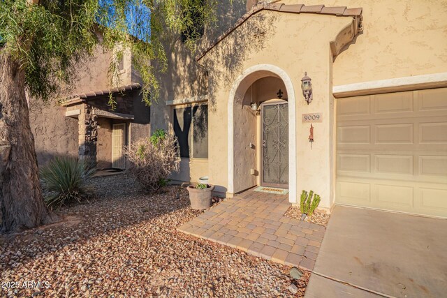 9009 S 57th Dr, Laveen, AZ 85339 - doorway to property with stucco siding, an attached garage, and driveway