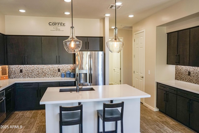 kitchen with light countertops, wood finished floors, stainless steel refrigerator with ice dispenser, and a sink