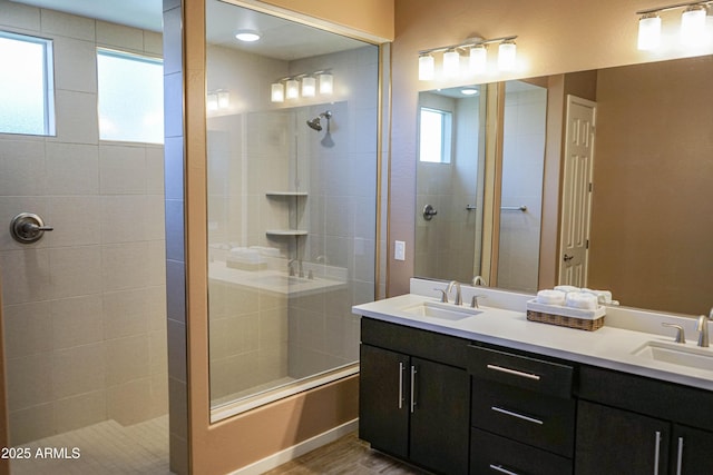 bathroom featuring double vanity, a tile shower, and a sink