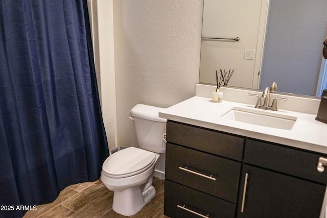 full bathroom with toilet, wood finished floors, vanity, and a textured wall