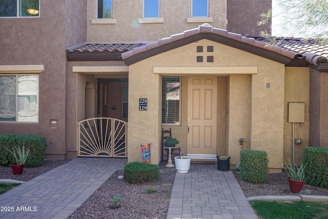 property entrance featuring a gate, stucco siding, and a tile roof