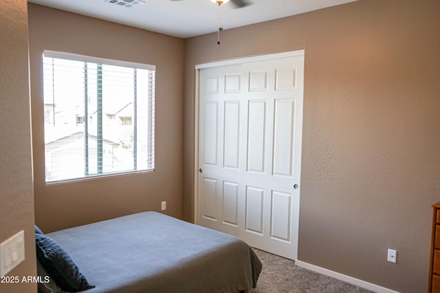 bedroom with visible vents, baseboards, carpet floors, a textured wall, and a closet