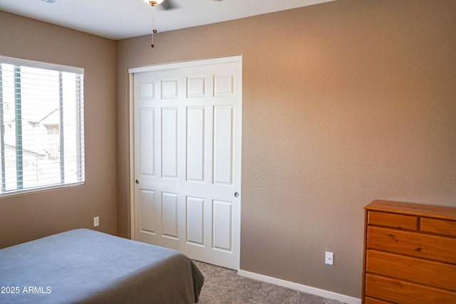 carpeted bedroom featuring a closet, baseboards, and a textured wall