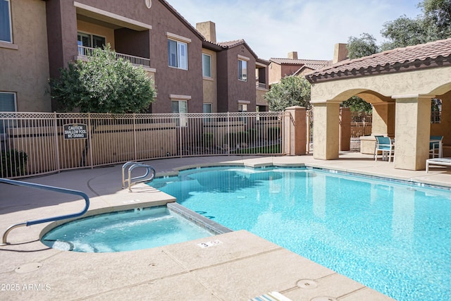 community pool featuring a patio area, a hot tub, and fence