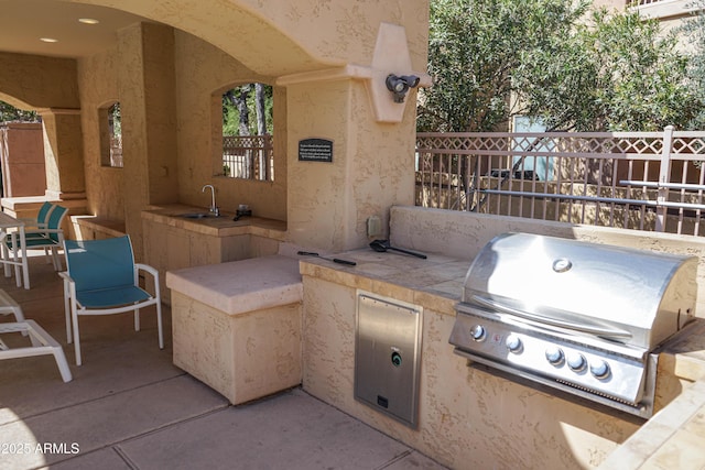 view of patio with area for grilling, fence, and a sink