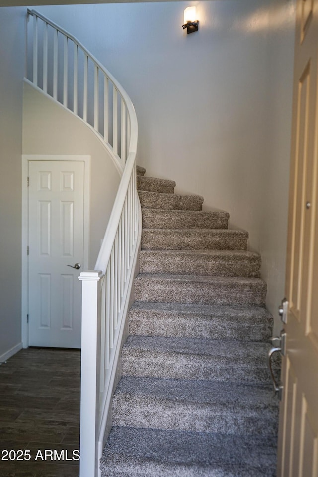 staircase featuring baseboards and wood finished floors