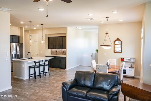 living room with recessed lighting, wood finished floors, visible vents, and baseboards