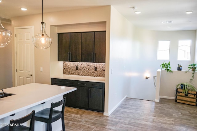 kitchen with light wood-type flooring, visible vents, pendant lighting, backsplash, and light countertops