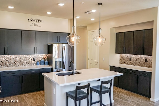 kitchen featuring light wood-style flooring, a sink, decorative light fixtures, stainless steel fridge with ice dispenser, and light countertops