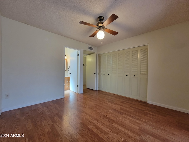 unfurnished bedroom with a closet, wood-type flooring, ceiling fan, and a textured ceiling