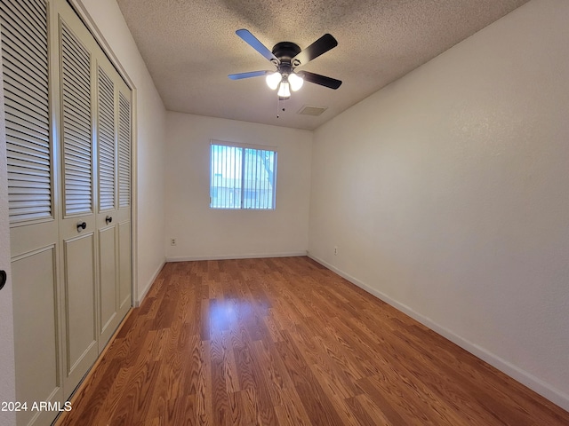 unfurnished bedroom featuring ceiling fan, a textured ceiling, a closet, and light hardwood / wood-style flooring