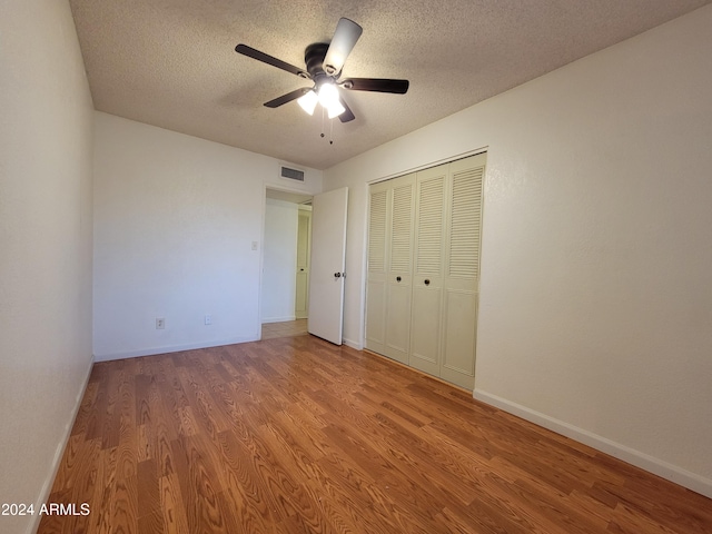 unfurnished bedroom with a textured ceiling, hardwood / wood-style floors, ceiling fan, and a closet