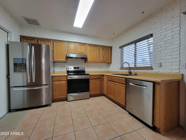 kitchen with stainless steel appliances, brick wall, and sink