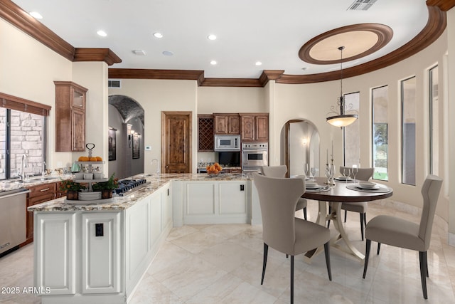 kitchen with sink, a center island, appliances with stainless steel finishes, pendant lighting, and white cabinets