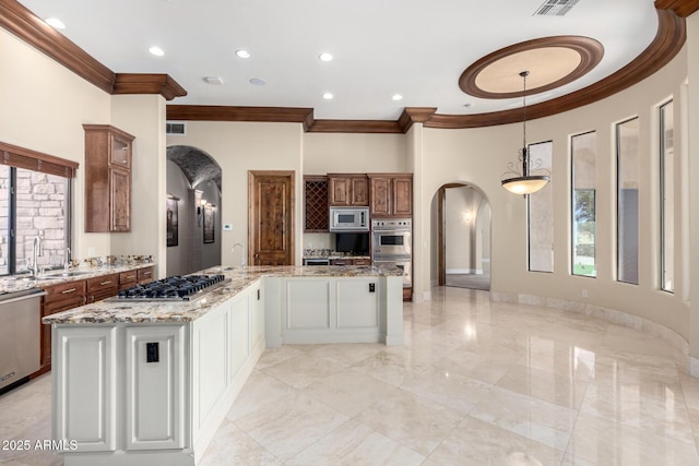 kitchen with sink, white cabinetry, light stone counters, appliances with stainless steel finishes, and a kitchen island