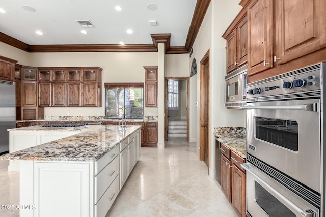 kitchen with a kitchen island, sink, light stone counters, stainless steel appliances, and crown molding