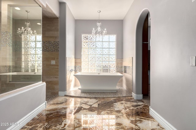 bathroom featuring tile walls, a tub, and a chandelier