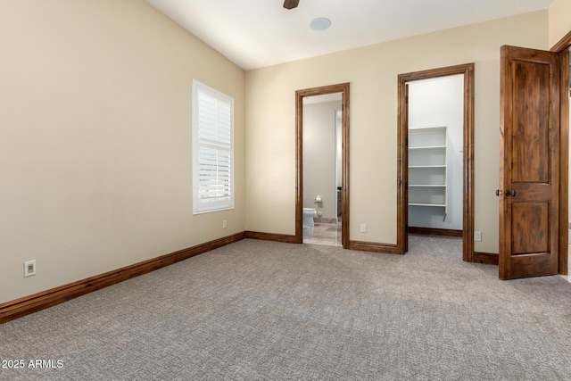 unfurnished bedroom with connected bathroom, a spacious closet, light colored carpet, and a closet