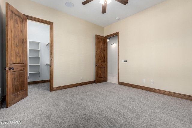 unfurnished bedroom featuring carpet, a spacious closet, ceiling fan, and a closet