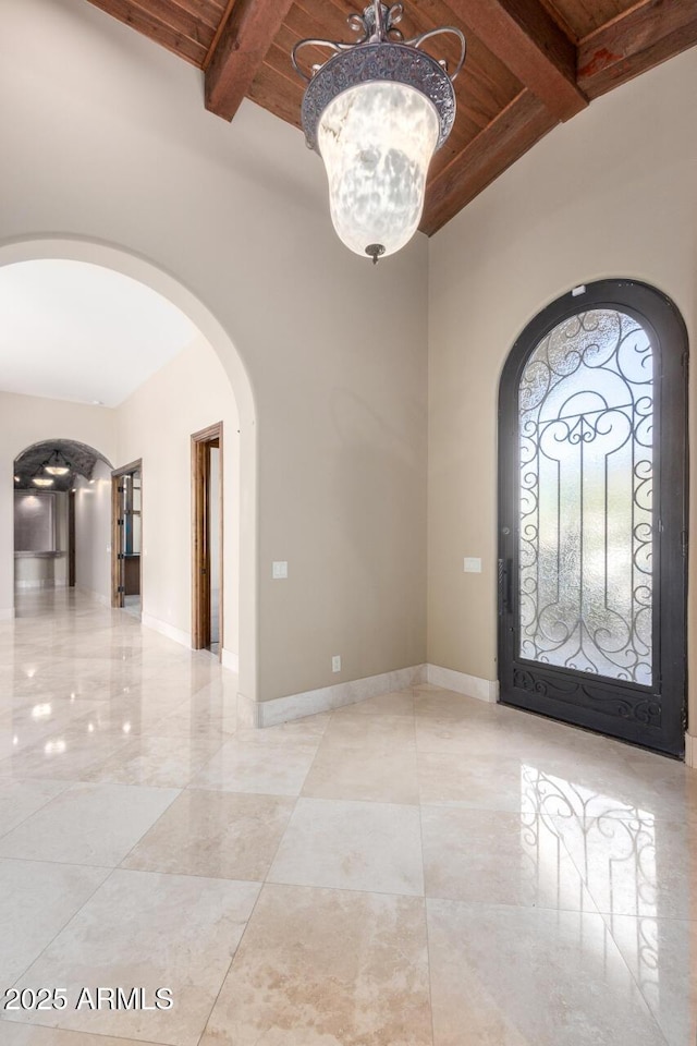 foyer entrance featuring beam ceiling, a notable chandelier, wood ceiling, and a high ceiling