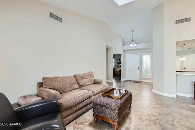 living room with an inviting chandelier, a skylight, and high vaulted ceiling