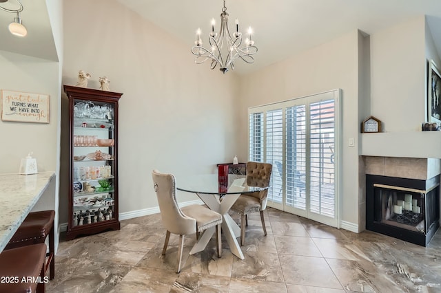 dining area featuring a tiled fireplace and an inviting chandelier