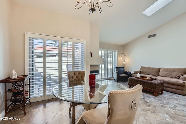 dining space with vaulted ceiling with skylight and a chandelier