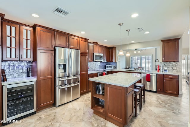 kitchen featuring appliances with stainless steel finishes, beverage cooler, a kitchen bar, hanging light fixtures, and kitchen peninsula