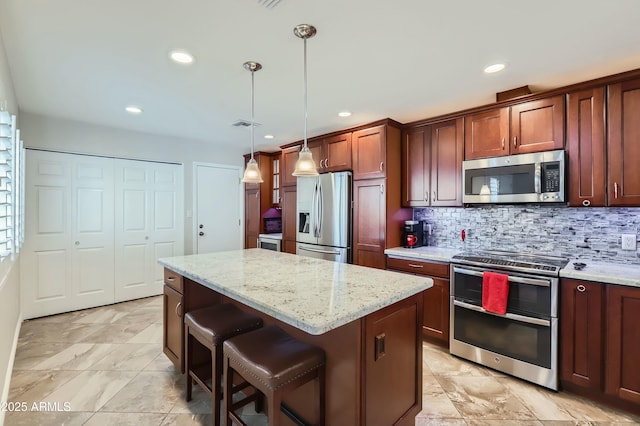 kitchen with light stone counters, a kitchen island, pendant lighting, stainless steel appliances, and decorative backsplash