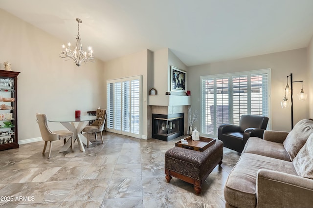 living room featuring vaulted ceiling, a tile fireplace, a chandelier, and plenty of natural light