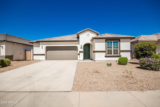 view of front facade featuring driveway, stucco siding, a tile roof, and an attached garage