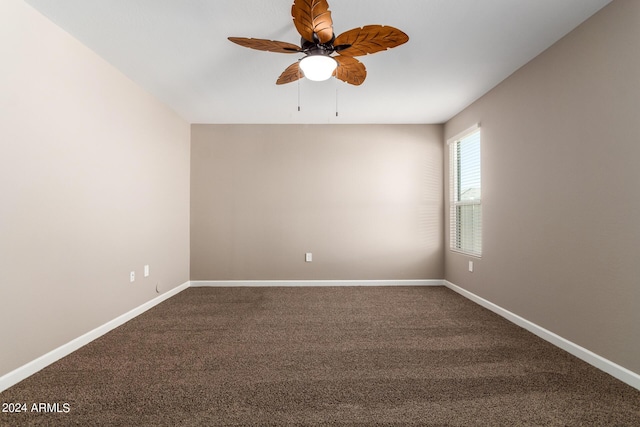 unfurnished room featuring a ceiling fan, baseboards, and dark carpet