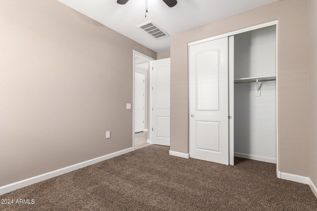 unfurnished bedroom with ceiling fan, a closet, and dark colored carpet