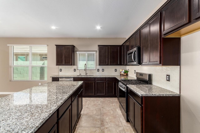 kitchen with a healthy amount of sunlight, a sink, stainless steel appliances, and light stone countertops