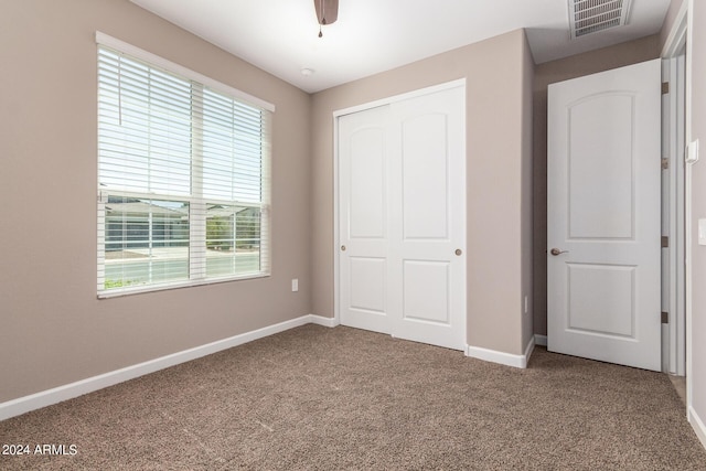 unfurnished bedroom featuring baseboards, carpet floors, visible vents, a ceiling fan, and a closet