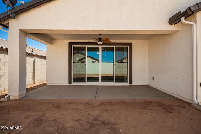 entrance to property with fence, ceiling fan, stucco siding, and a patio area