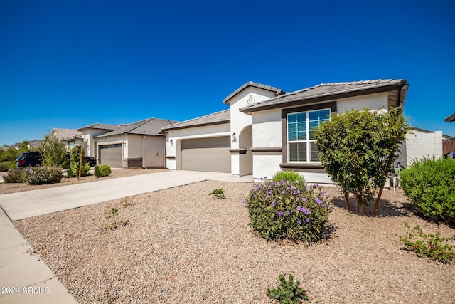 view of front facade featuring a tiled roof, stucco siding, concrete driveway, and a garage