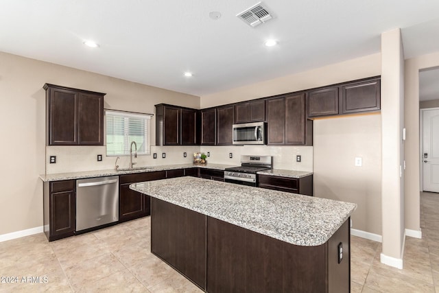 kitchen with a kitchen island, a sink, visible vents, dark brown cabinetry, and appliances with stainless steel finishes