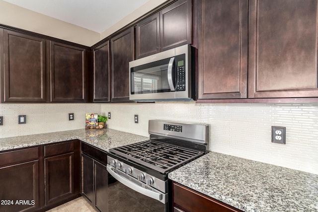 kitchen featuring light stone countertops, dark brown cabinetry, decorative backsplash, and stainless steel appliances