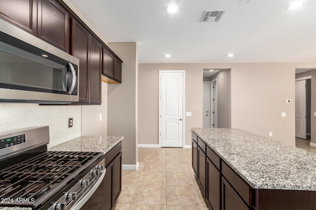 kitchen featuring visible vents, light stone counters, dark brown cabinets, and appliances with stainless steel finishes