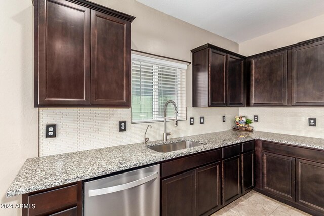 kitchen with dark brown cabinetry, dishwasher, sink, and light stone counters