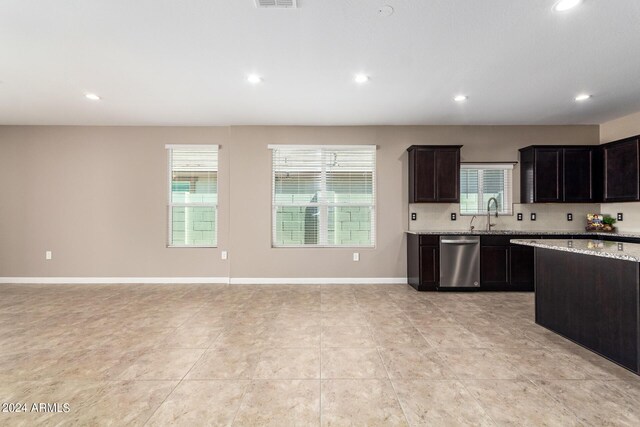 kitchen with decorative backsplash, light stone counters, dishwasher, light tile patterned floors, and dark brown cabinetry