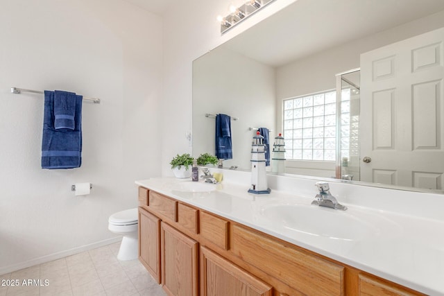 bathroom with toilet, a shower stall, double vanity, and baseboards