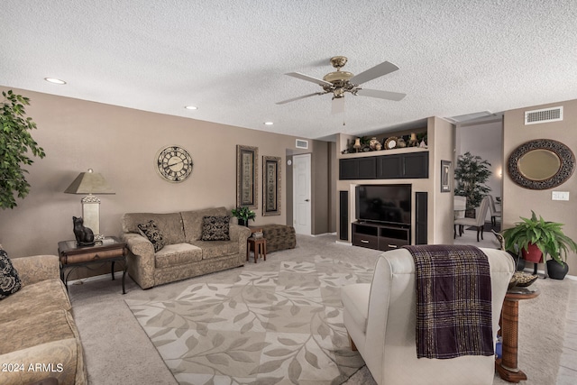 carpeted living room featuring a textured ceiling and ceiling fan