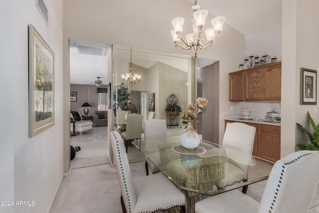 dining room featuring light colored carpet, ceiling fan with notable chandelier, and high vaulted ceiling