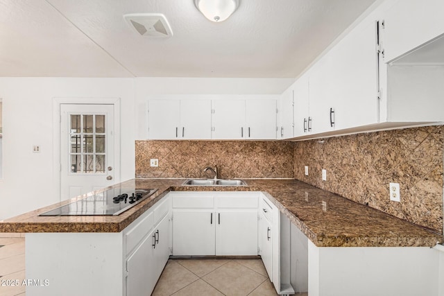 kitchen with black electric cooktop, decorative backsplash, white cabinets, and a sink